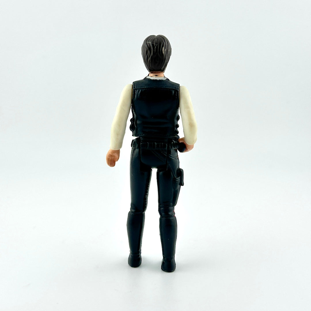 action figure in black pants and vest with white shirt and black gun against white background. 