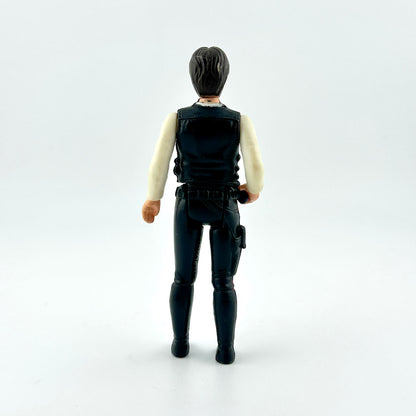 action figure in black pants and vest with white shirt and black gun against white background. 