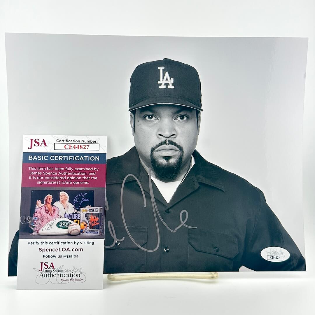Photo of Ice Cube wearing a black cap with a logo, next to a JSA certification card on a white background