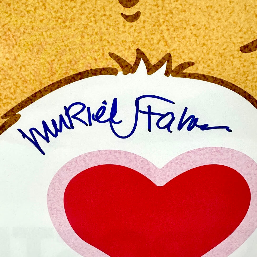 Close-up of a product with a red heart and blue marker signature on a Care Bear poster