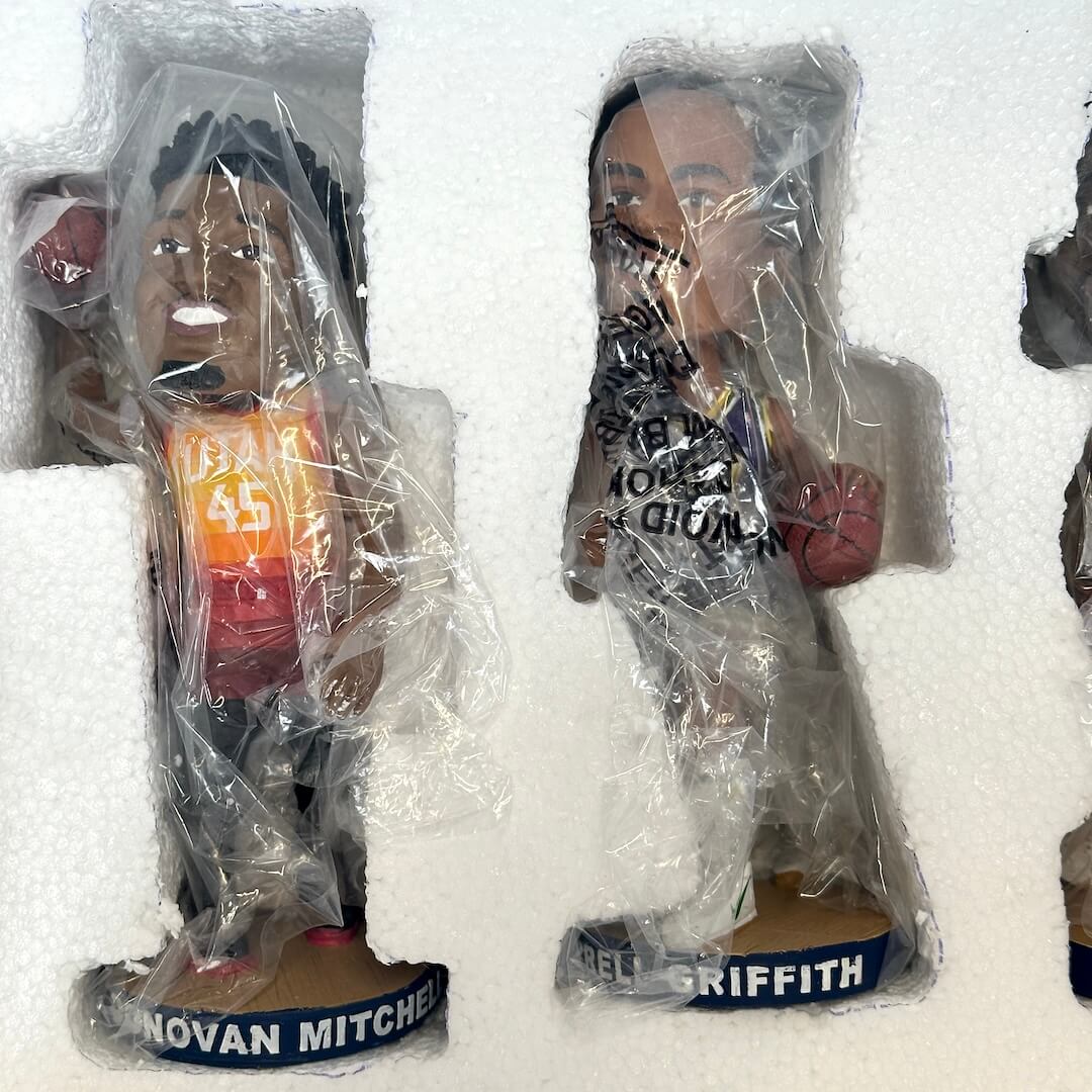 Two sports figures wrapped in plastic, one with '45' and the other with 'Griffith', on a white background.