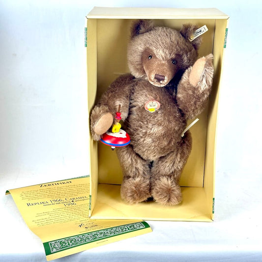 Vintage teddy bear in cream colored box with certificate on white backrgound. 