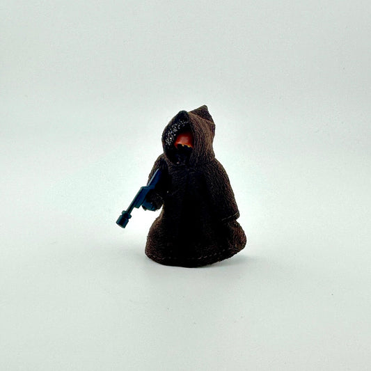 Toy figure in a dark hooded outfit holding a blue weapon on a white background