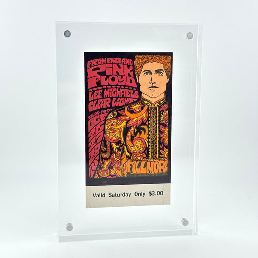 Vintage Pink Floyd ticket in clear frame. Ticket has image of man in decorative jacket surrounded by stylized text. 