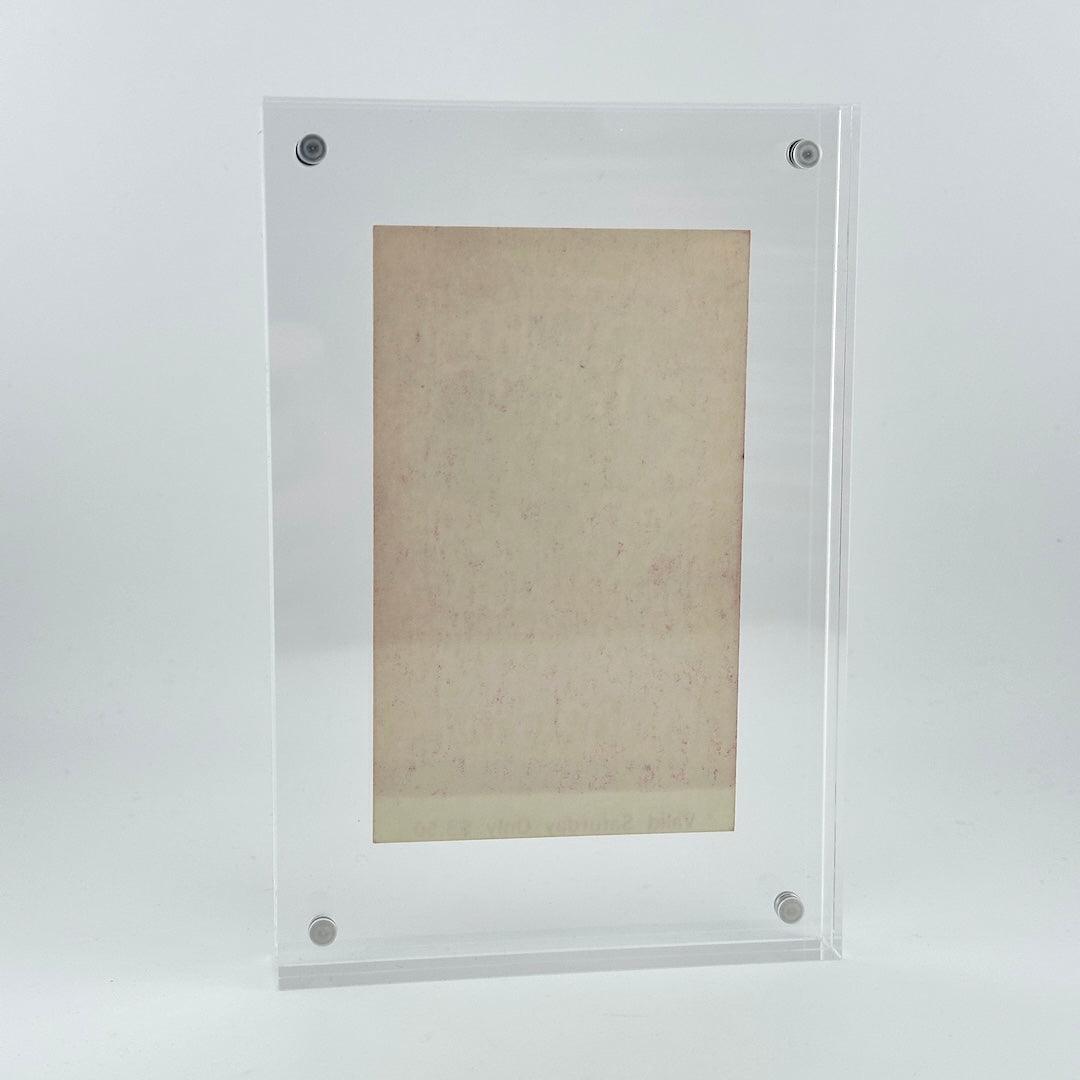 backside of clear acrylic frame with vintage ticket in center showing no obvious damage and pristine frame. 