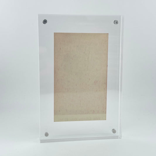 backside of clear acrylic frame with vintage ticket in center showing no obvious damage and pristine frame. 