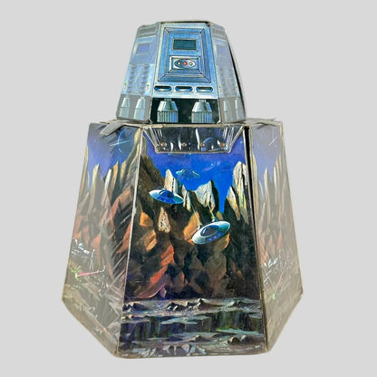Vintage playset folded into rough cylinder shape with smaller portion on top. Decorated with Sci-Fi elements. 