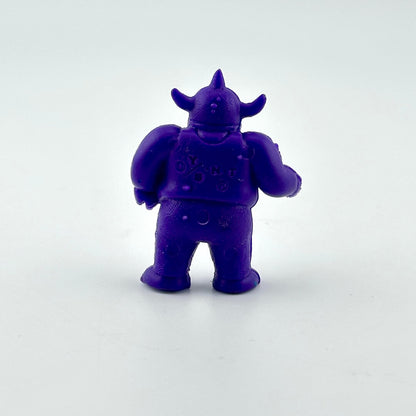 A small purple monster figurine shown from the back, standing on a plain light gray background.