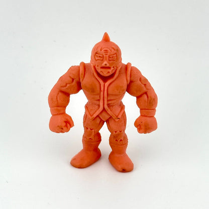 An salmon-pink plastic action figure of a muscular masked wrestler, photographed against a plain white background.