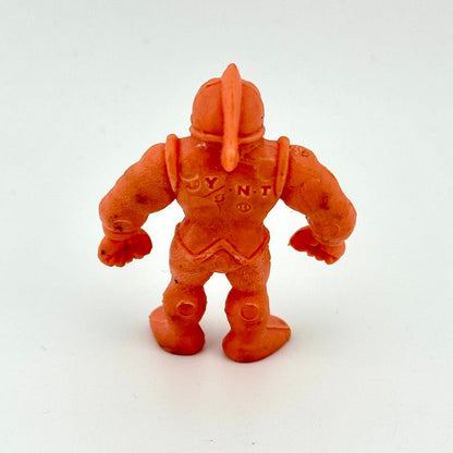 An orange plastic action figure of a muscular warrior with a helmet, shown from the back on a white background.