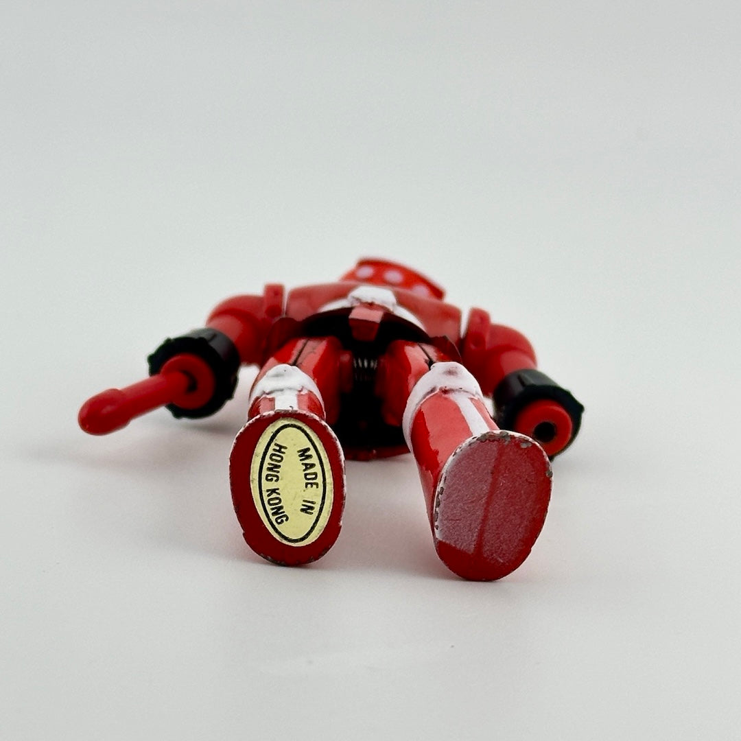 Image of bottom of feet of red & white diecast robot to show gold oval sticker, reading "Made in Hong Kong"