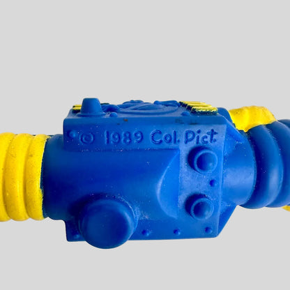 Blue and yellow toy hose nozzle with '1989 Col. Pict' text on a white background