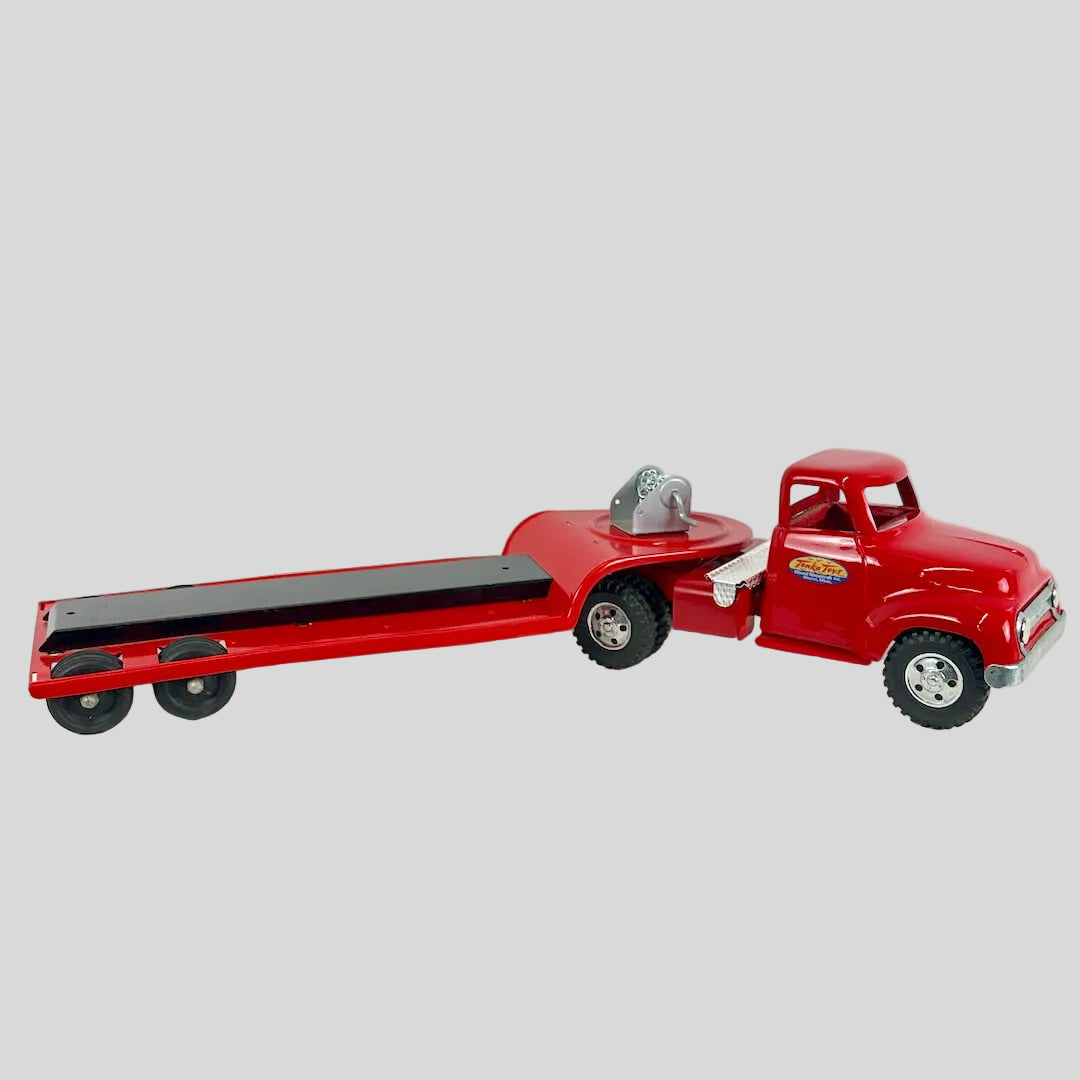 Red toy truck with a flatbed trailer on a white background