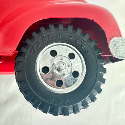 Close-up of a red toy truck with a black tire and silver rim on a white background
