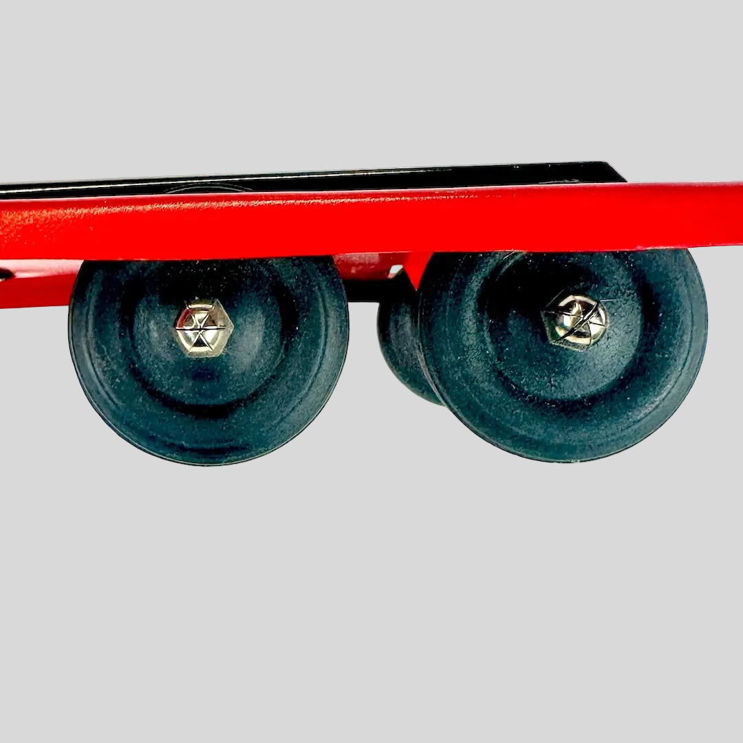 Red metal trailer with two black wheels on a white background