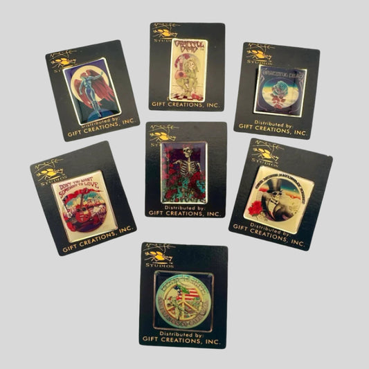 Seven hard enamel pins featuring Grateful Dead art by Stanley Mouse on black card backs with gold text & logos.