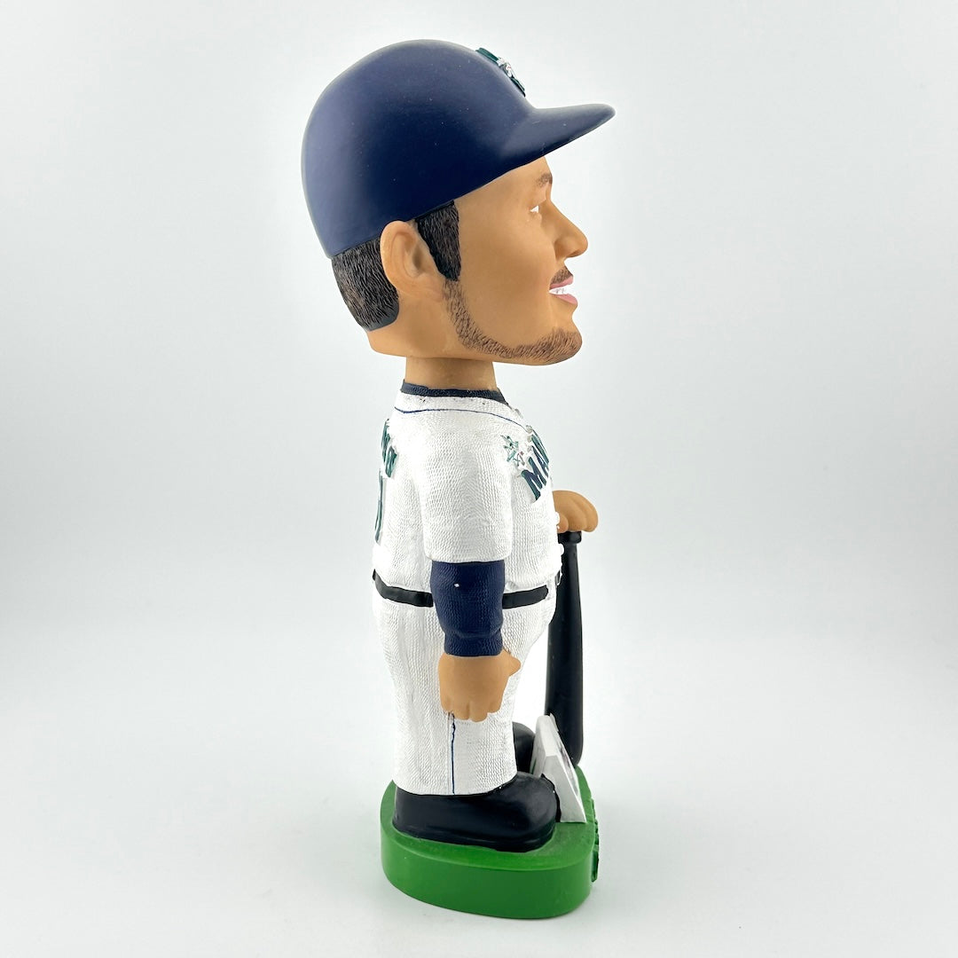 Bobblehead of a baseball player in a white and navy uniform with a green base on a white background