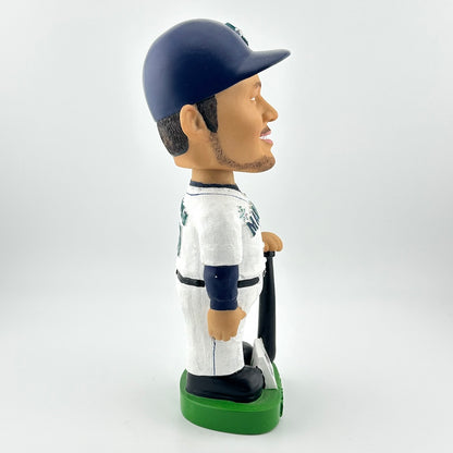 Bobblehead of a baseball player in a white and navy uniform with a green base on a white background
