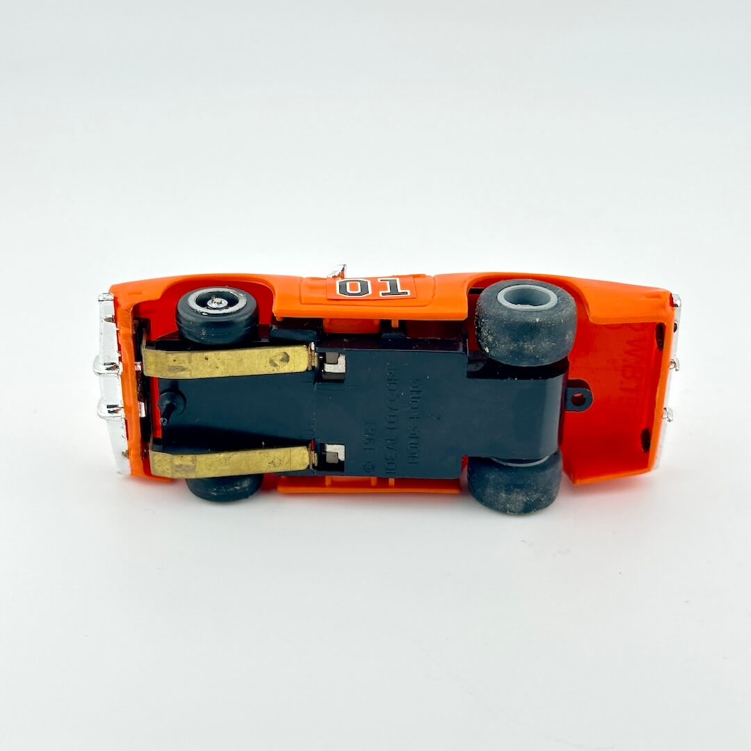 Close-up of a toy car's undercarriage with visible suspension components on a white background
