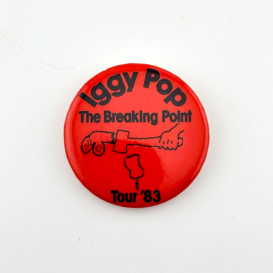 Red button with black text and graphic, featuring 'Iggy Pop The Breaking Point Tour '83' on a white background.