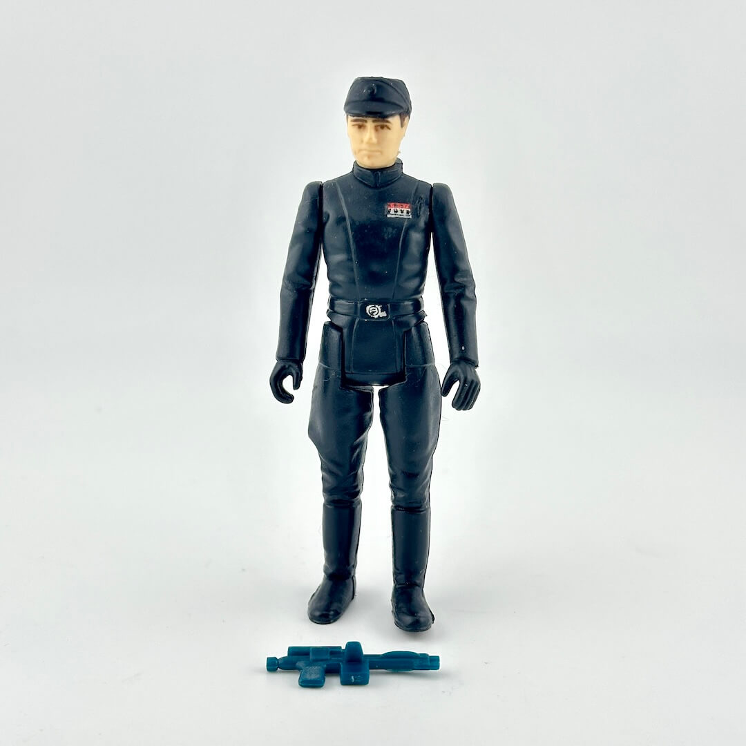 A Star Wars action figure of a man in military uniform with weapon at feet against white background.