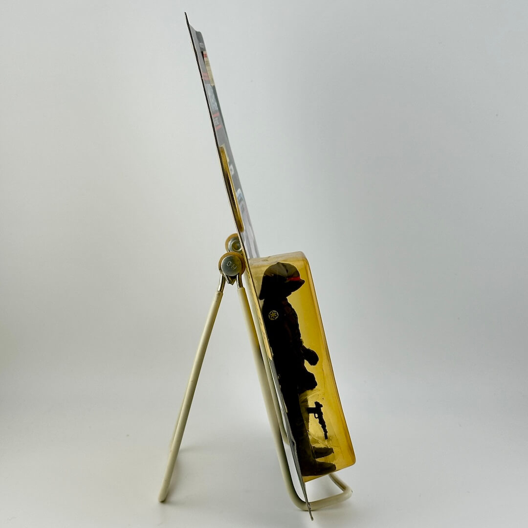 Side view of Star Wars action figure still in packaging on easel against white background.