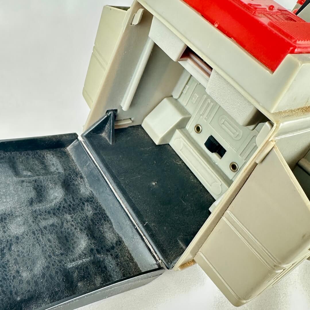 Close up of back compartment of toy vehicle against gray background.