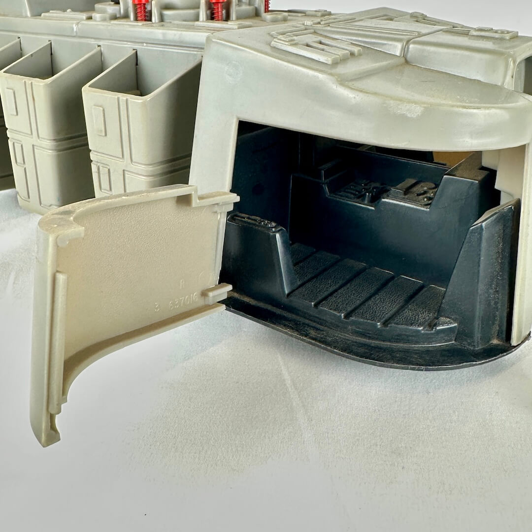 Close up of interior of one compartment of toy spaceship against white background.