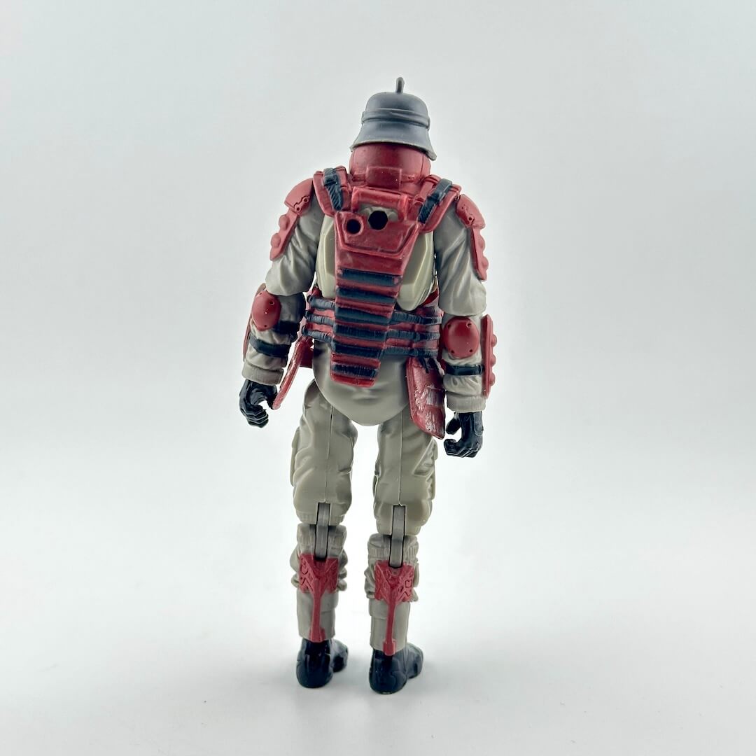 Action figure of a soldier shown from the back, wearing a beige jumpsuit with red armor plating, a gray helmet, and black boots.