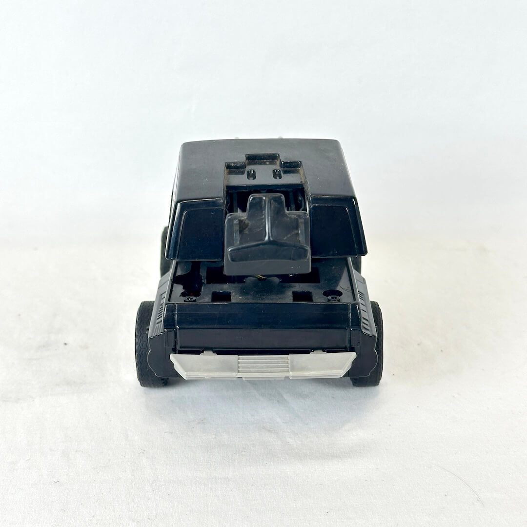 A black plastic toy vehicle, photographed from the rear on a white background.