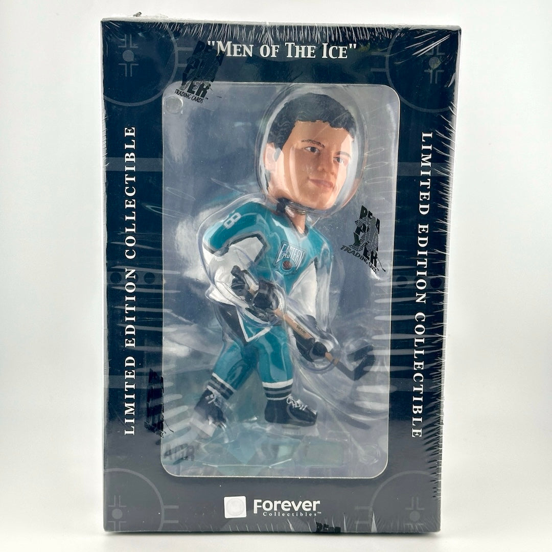 Hockey player wearing teal & white uniform holding stick still in box wrapped in plastic.