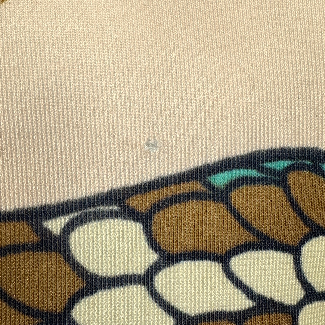 Close-up of a fabric with a small hole above snake. 