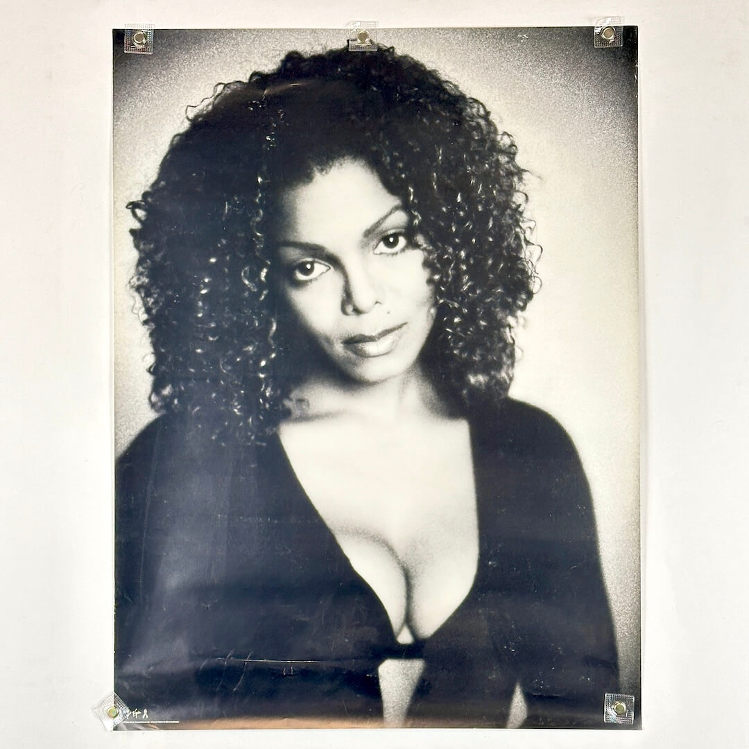 Black and white poster portrait of Janet Jackson in black shirt. 