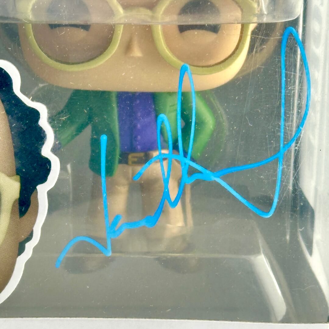 Toy figure in a clear display case with a blue signature overlay