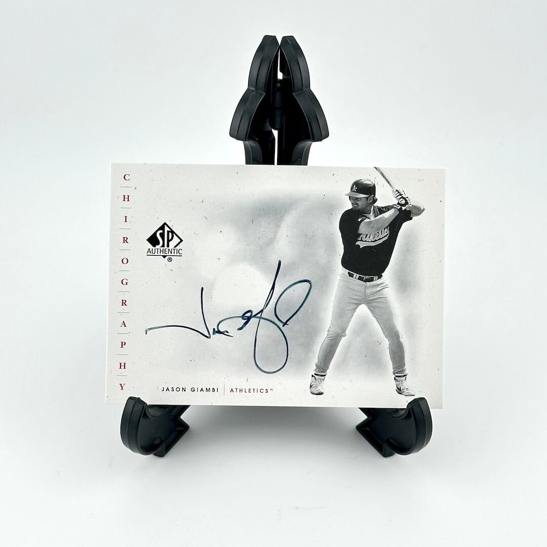 Baseball trading card of a player in action with a signature, held by black card holders on a white background.