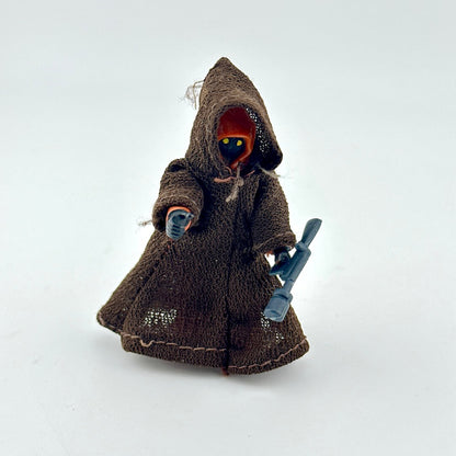 Toy figure in a brown hooded outfit with a blue weapon on a white background