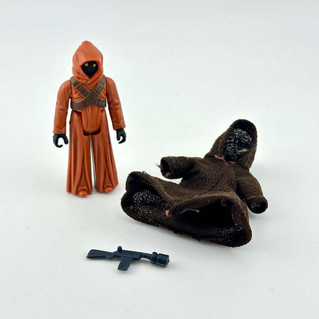 Jawa action figure with cape and gun on white background. 