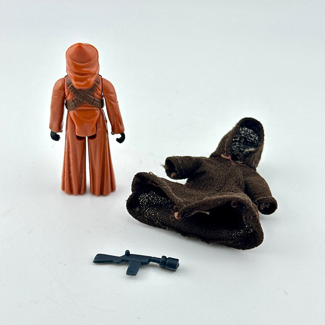 Jawa action figure with cape and gun on white background.
