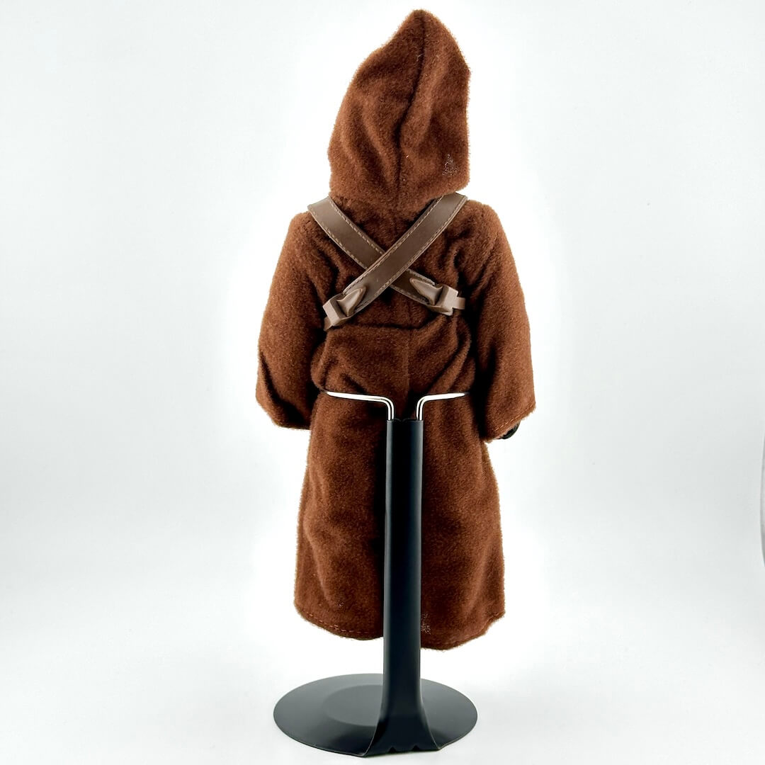 8 inch Jawa doll/figure in brown robe with gun held aloft by doll stand. 