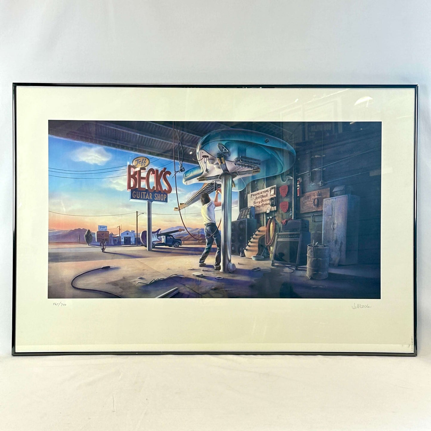 Framed artwork of a person playing guitar in front of a guitar shop sign.