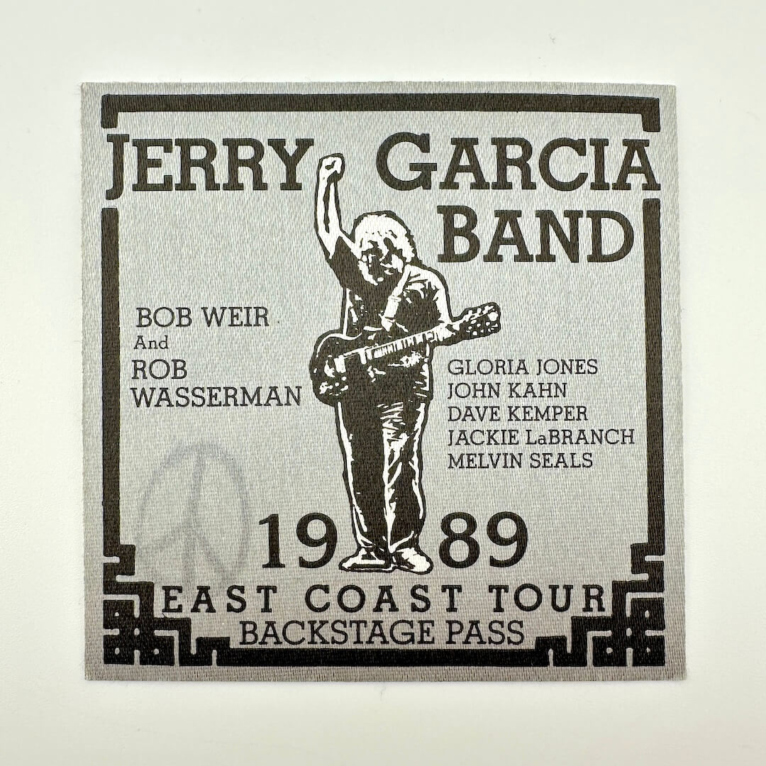 Jerry Garcia Band backstage pass with a silhouette of a person playing guitar on a light gray background