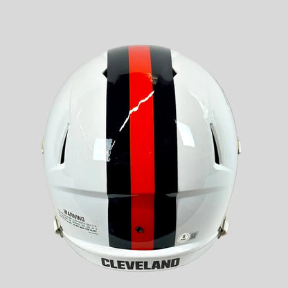 Back view of white football helmet with black and orange stripes down center with warning and authentication sticker. 