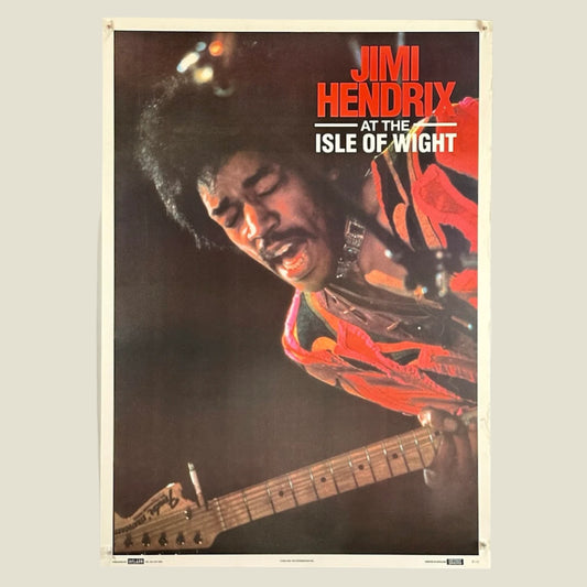 Poster features photo of Hendrix playing guitar & singing, wearing red. "Jimi Hendrix" in red, "At the Isle of Wight" in white. 