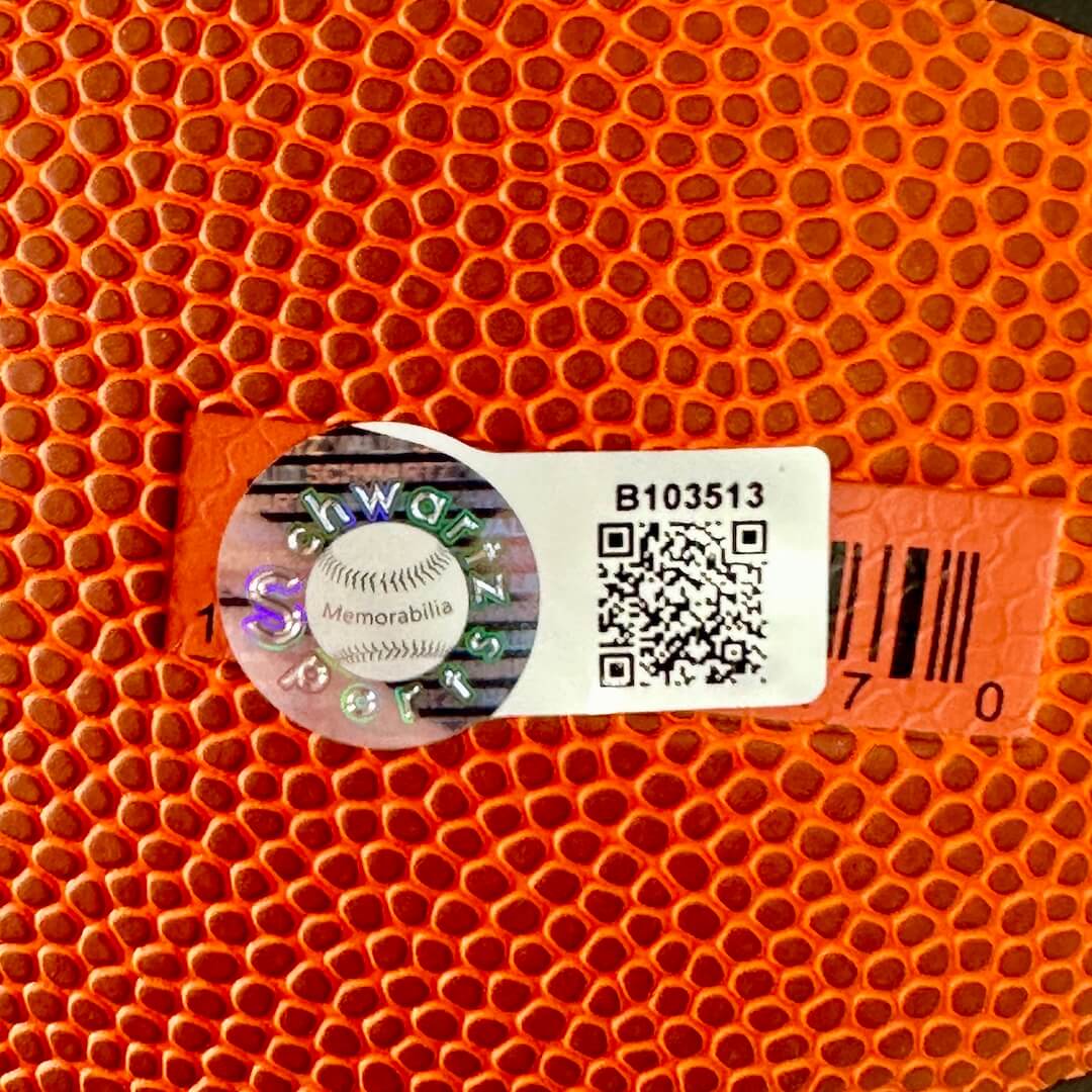 Close-up of an orange sports ball with a label featuring a QR code and text.