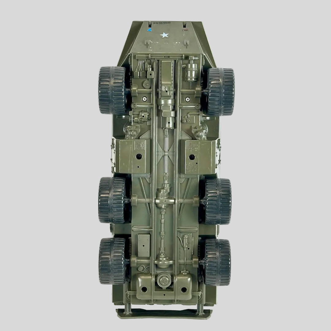 An underside view of a military armored vehicle model, showing detailed chassis, suspension, and six dark wheels.