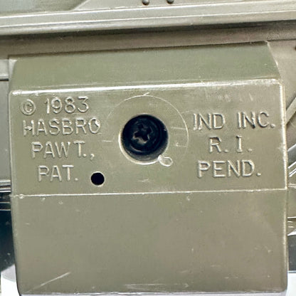 Close-up of a vintage Hasbro product in olive green plastic with embossed text reading '© 1983 HASBRO PAW T. PAT.