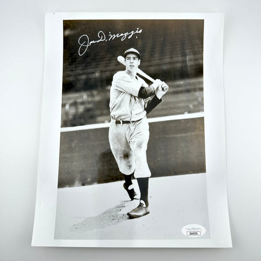 Black and white photo of a baseball player holding a bat, signed by Joe DiMaggio, on a white background.