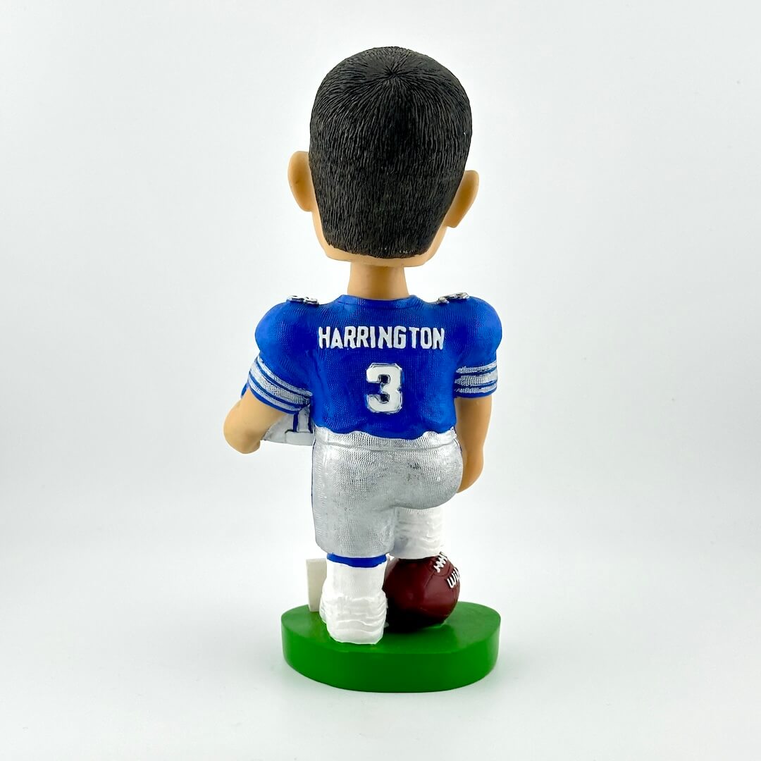 Back view of football player bobblehead holding helmet against white background. 