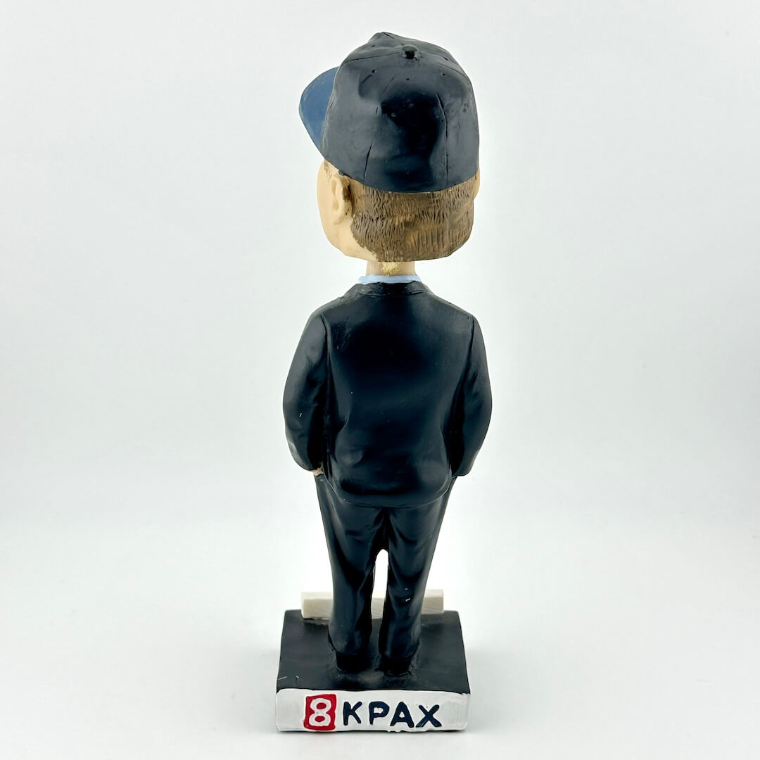 Bobblehead figure with a cap and suit on a white background, branded '8KPAX'.