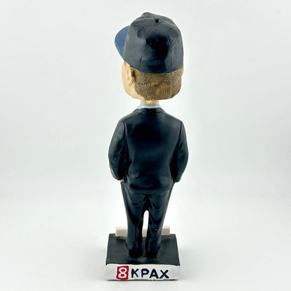 Bobblehead figure with a cap and suit on a white background, branded '8KPAX'.